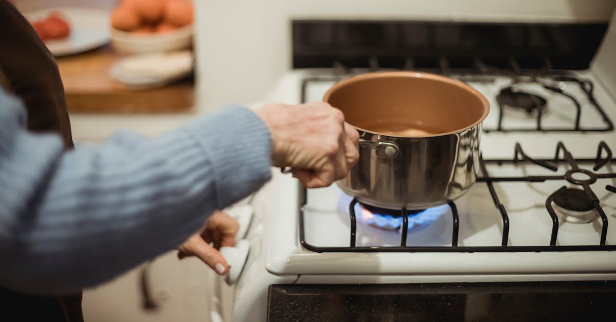 a woman cooks using a saucepan on a modern gas stove indoors showcasing domestic kitchen activity